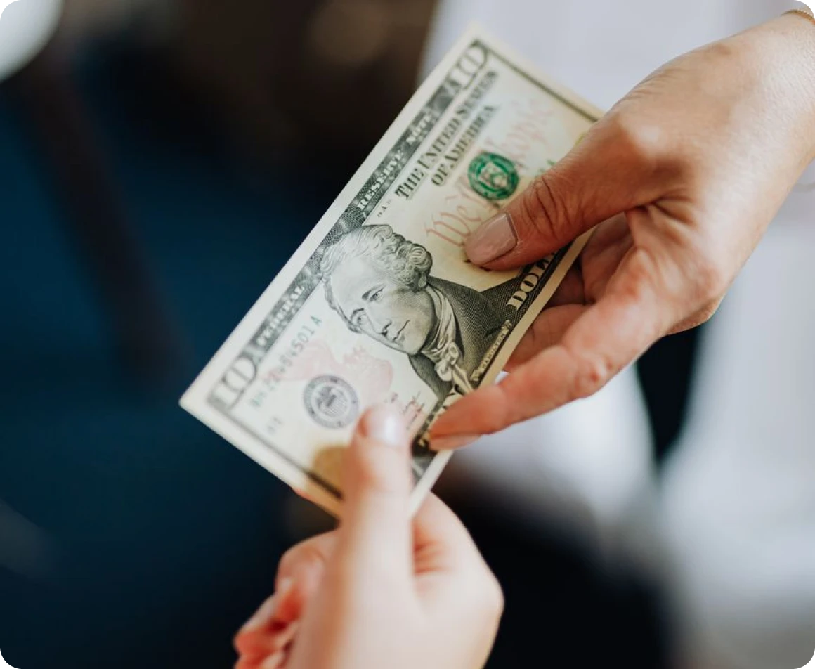A person handing a $100 bill to a pawn shop owner in Brockton MA