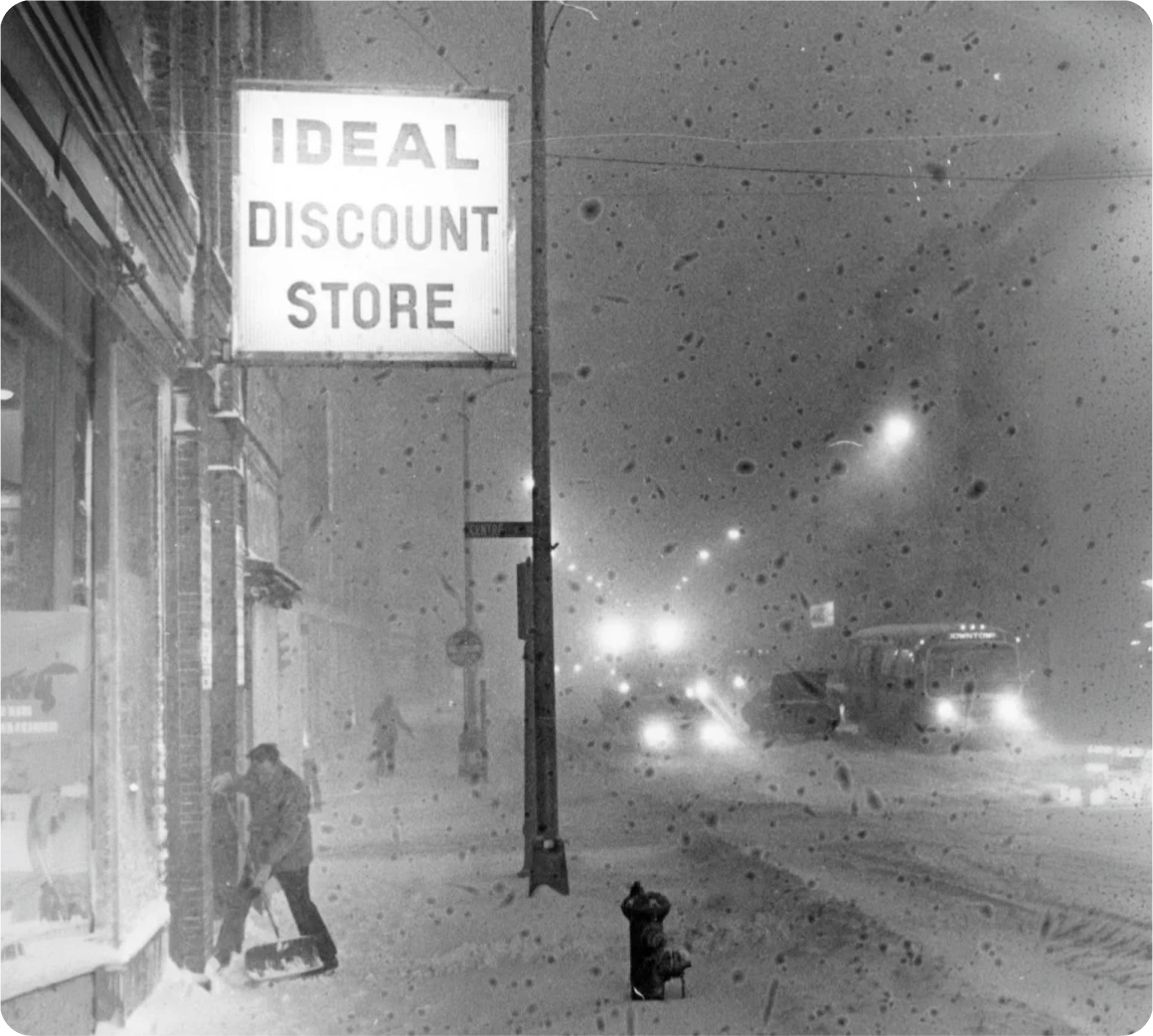 A man shovels snow in front of an Ideal Discount Store in Brockton MA