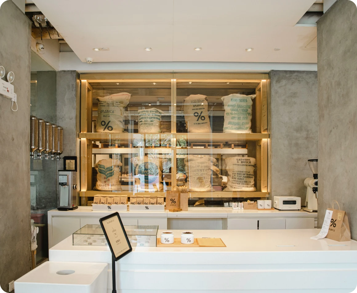 Brockton MA A modern coffee shop interior with a large glass window displaying coffee beans in bags with the % symbol on them